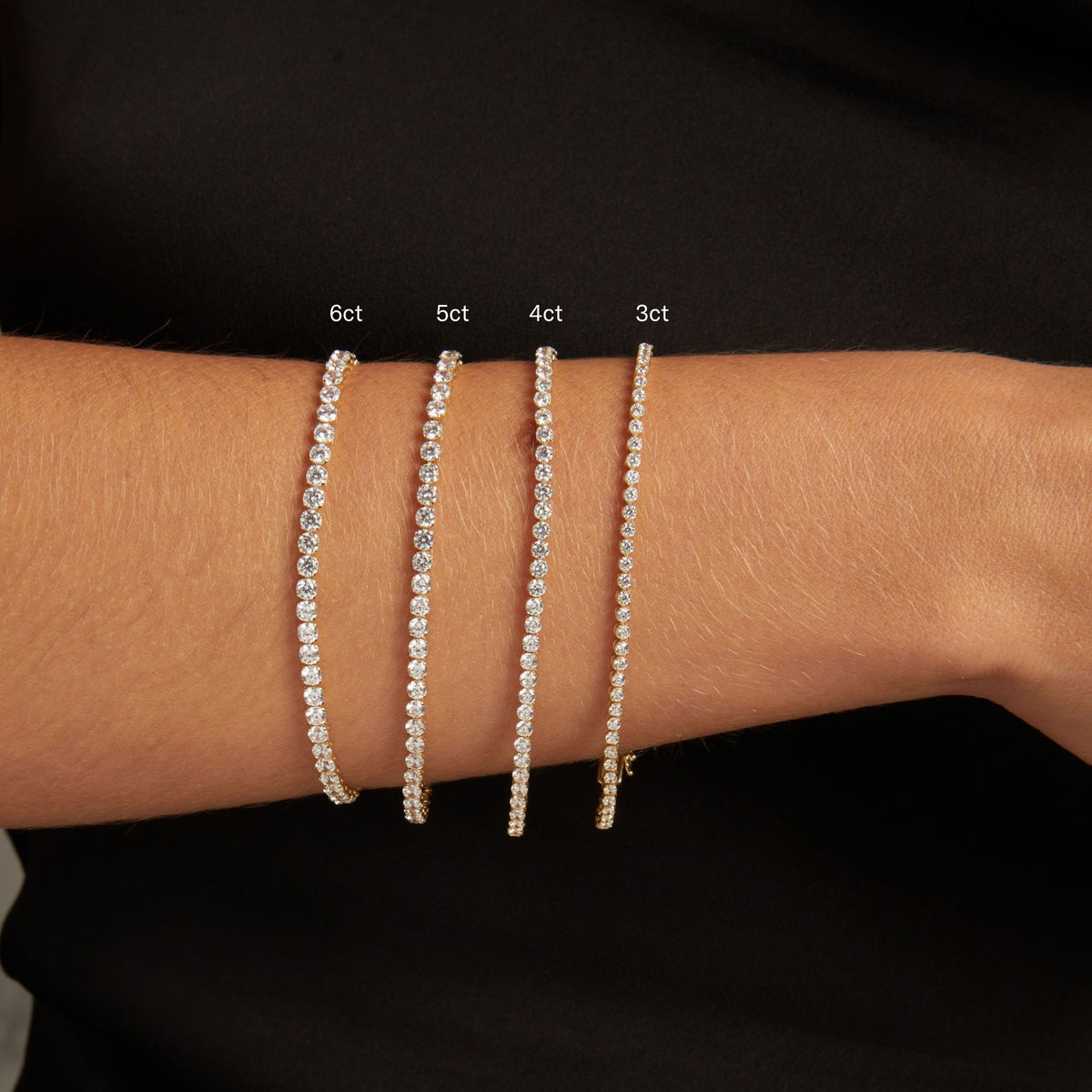 Model. Close up of a woman's wrist with four dainty diamond tennis bracelets. 