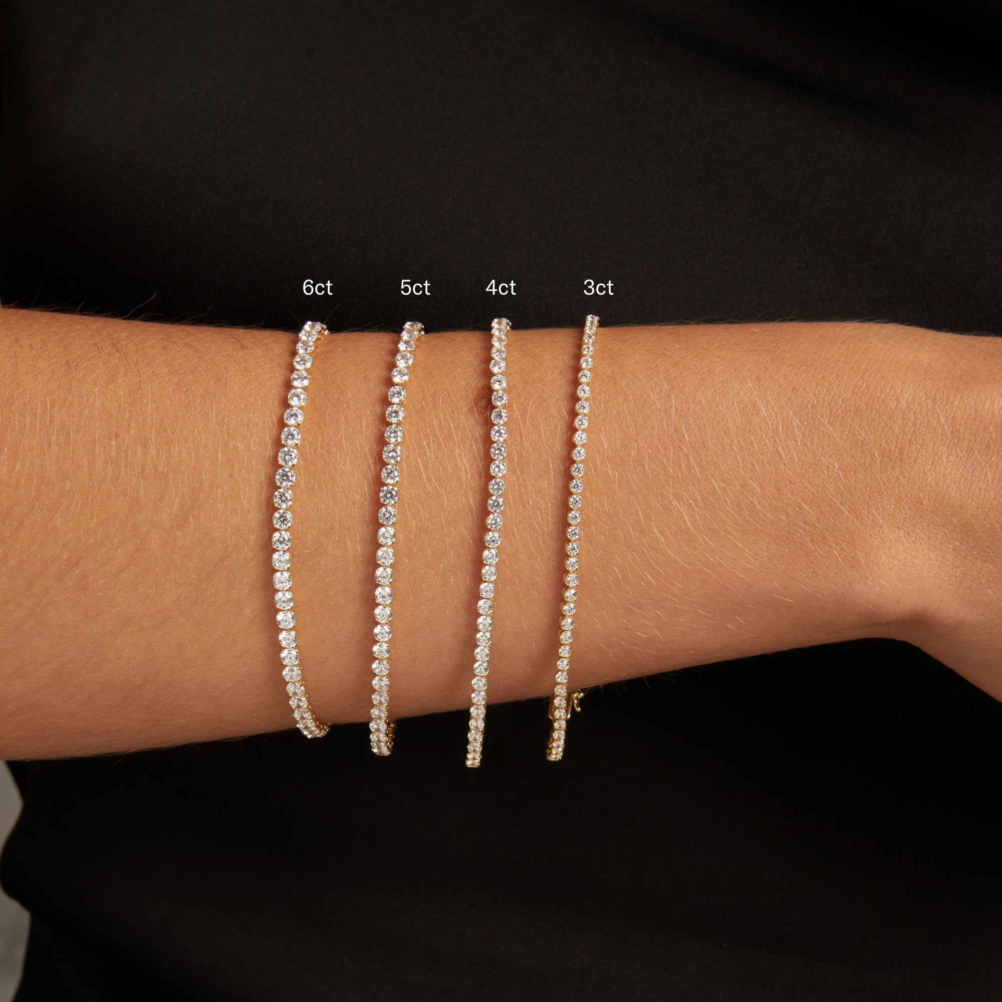 Model. Close up of a woman's wrist with four dainty diamond tennis bracelets. 