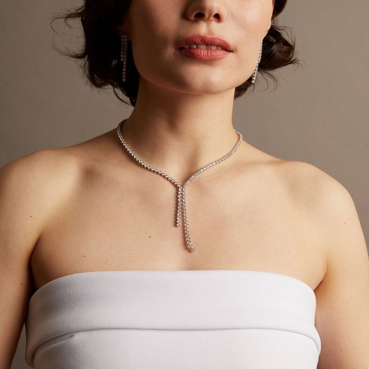 Model. Woman wearing a tennis necklace against a neutral background