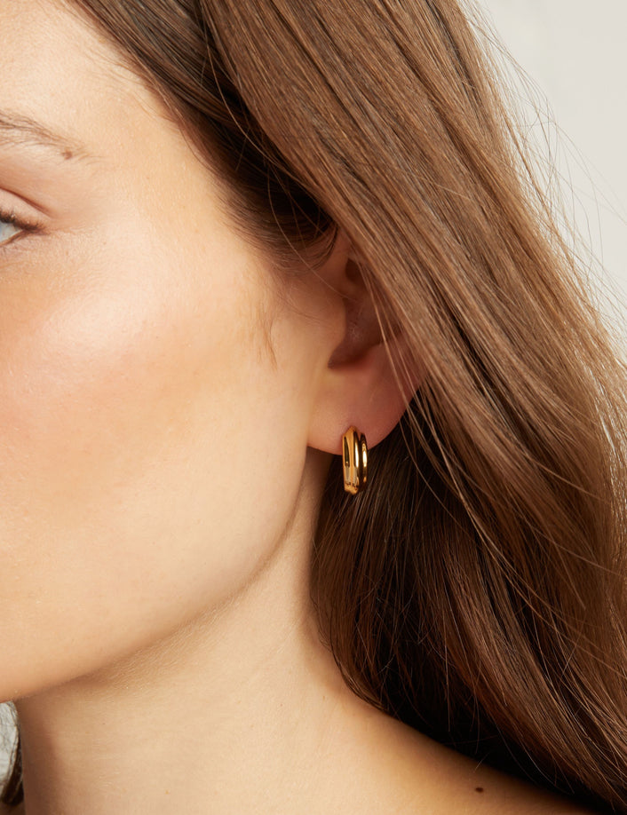 Close up of a person wearing gold hoop earrings.