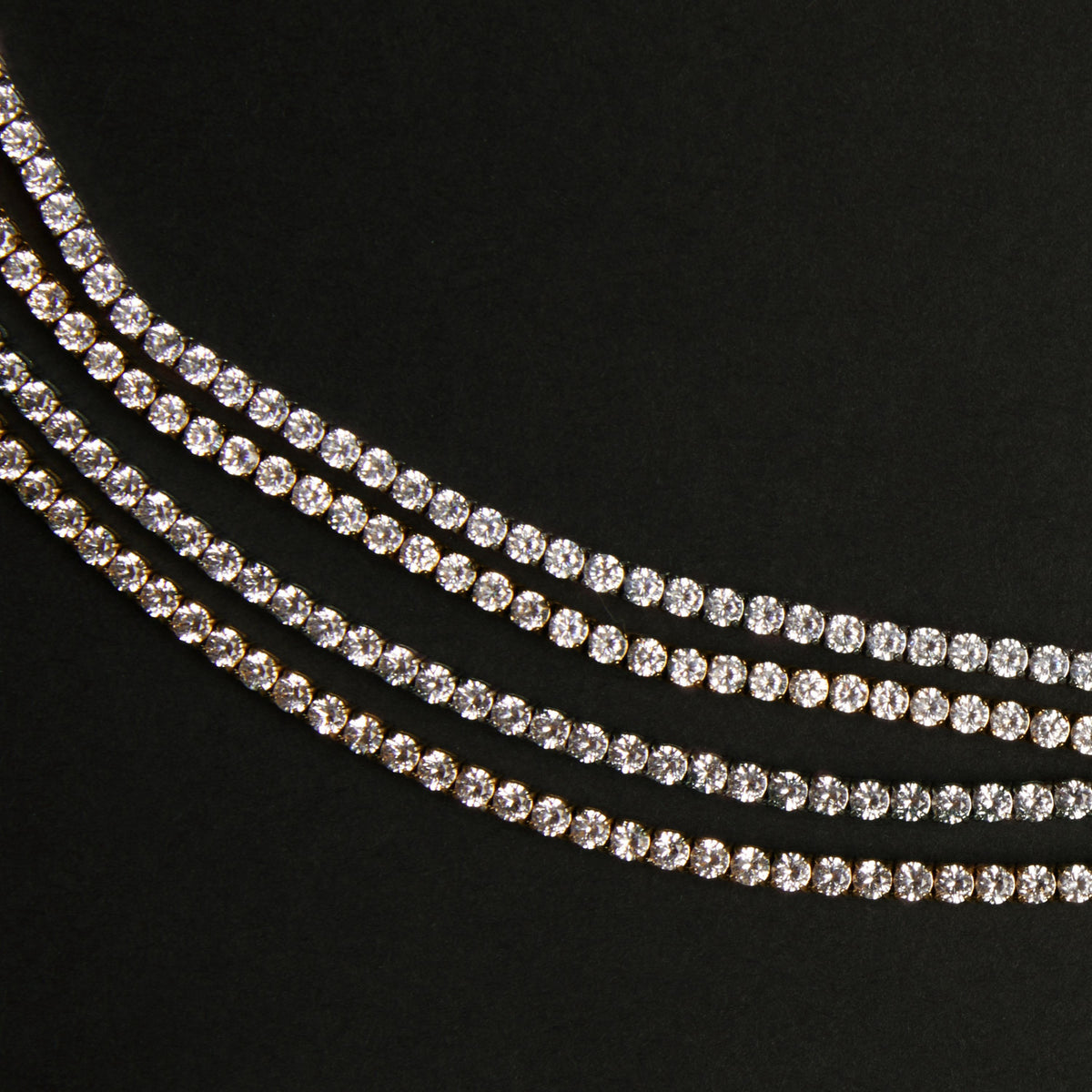 Model. Three strands of white sapphire tennis bracelets on a black background