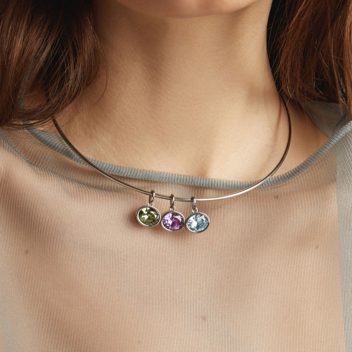 Model. Necklace with three colorful gemstones worn by a person
