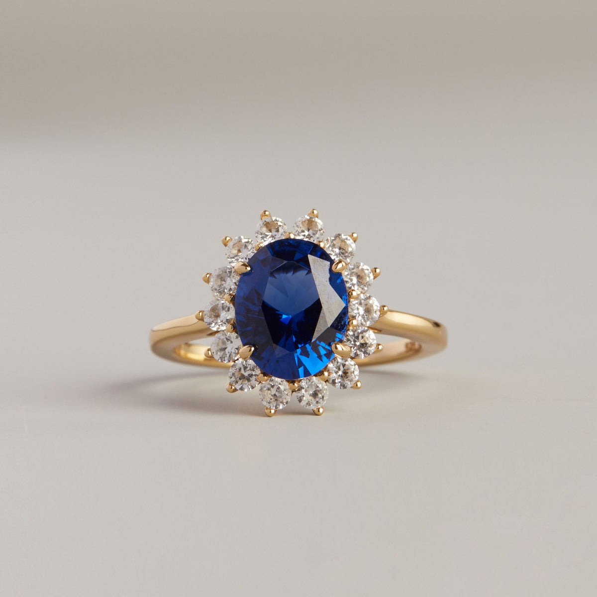 Model. Close up of a blue sapphire ring on neutral background.