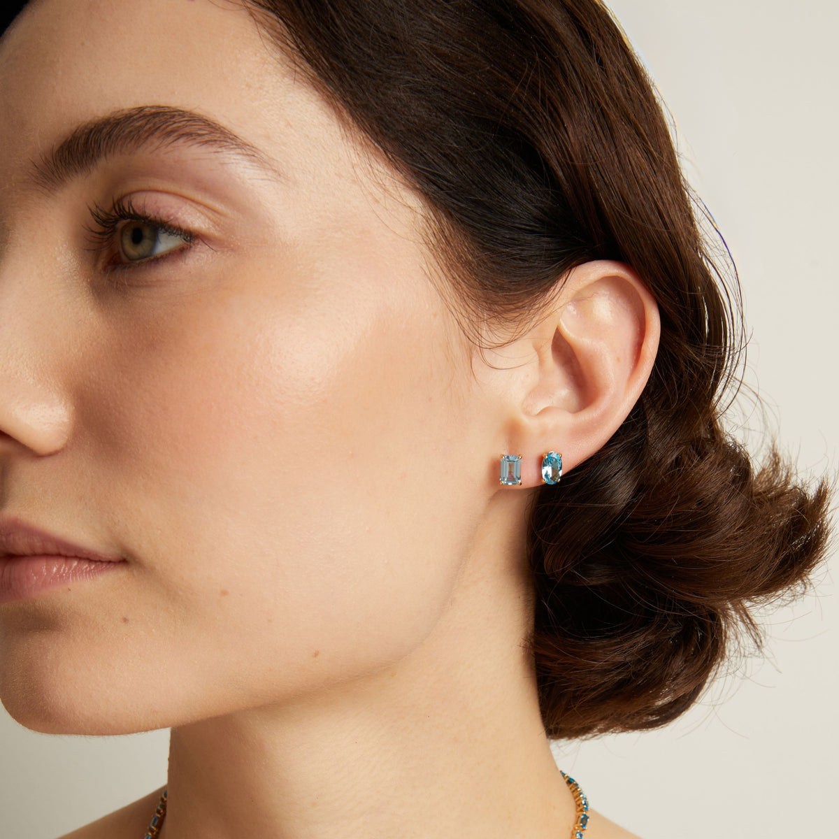 Woman wearing two blue stud earrings. Model
