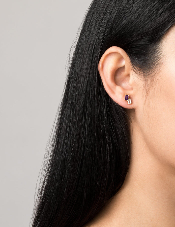 Model. Close-up of an ear with a small earring on a gray background