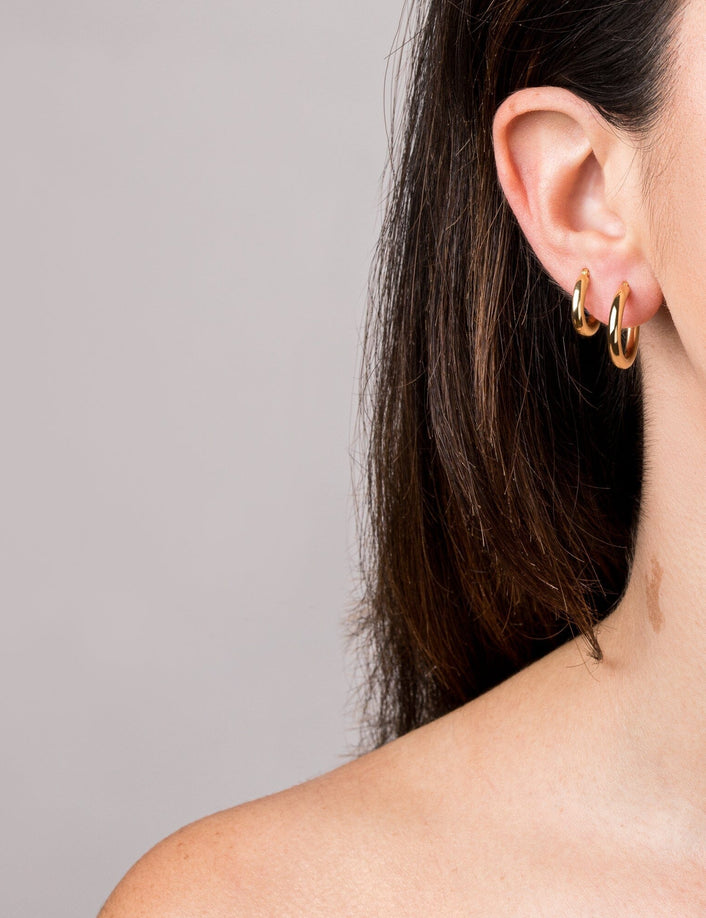 Woman wearing two gold hoop earrings