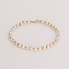 Video of gold knot pearl bracelet on white background.