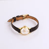 Video of a black leather watch with gold face on white background.