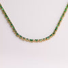 Video of green tennis necklace on white background.