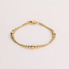 Video of a gold ball chain bracelet on white background.