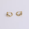 Gold bezel huggie earrings on neutral background
