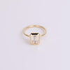 Emerald shape diamond ring with gold band on white background 