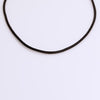 Black cord necklace on neutral background