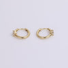 Gold huggies with white sapphire gemstone on neutral background
