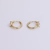 Gold huggies with white sapphire gemstone on neutral background