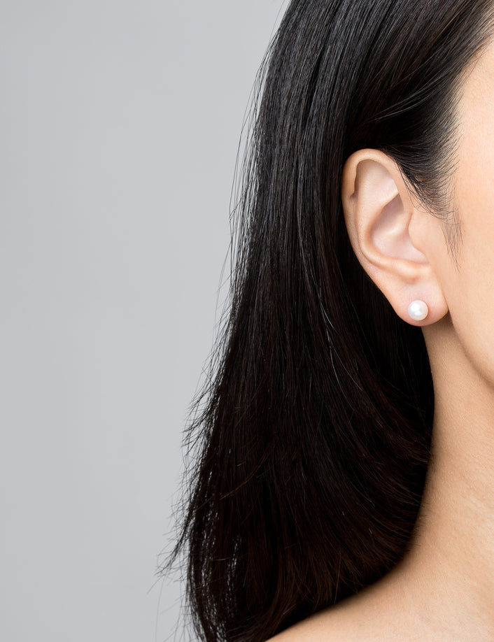 Model. Woman wearing pearl earring on neutral background